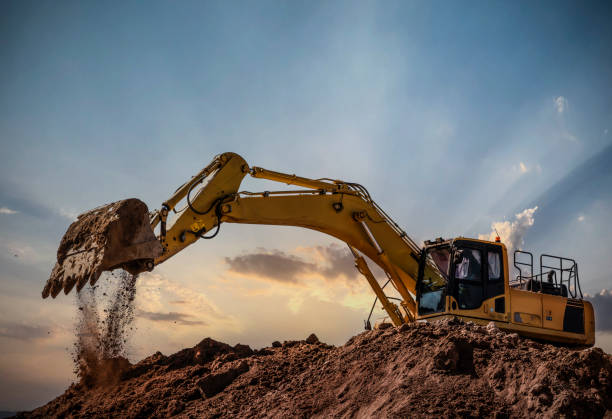 Heavy construction equipment against dramatic sunset sky representing infrastructure development