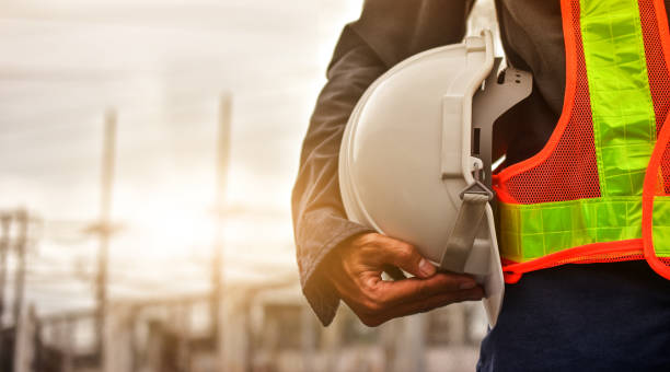 Professional construction worker in safety gear holding hard hat