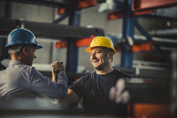 Two industrial workers in hard hats collaborating and celebrating teamwork